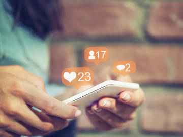 hands holding phone with social media bubbles