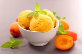 a-bowl-of-peach-sorbet-with-cut-peaches-next-to-it